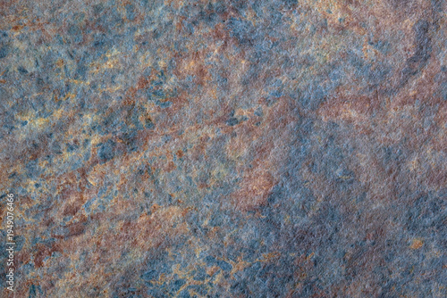 Rough, textured surface with blue and brown color scheme. surface appears to be made of stone or concrete