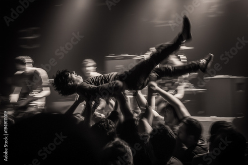 Early 2000s rock concert, crowd surfing fans, stage lights, smoke machines, nu-metal band performance, raw documentary photography