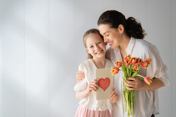 Happy Mother and Daughter Hugging with Card and Tulips Mother's Day Celebration