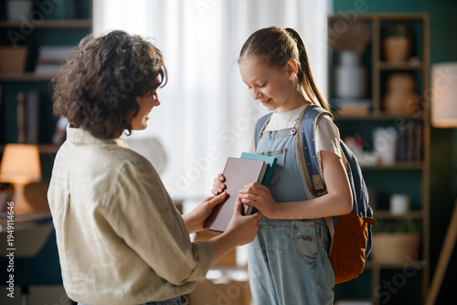 Bild auf Leinwand Happy Teacher Giving Books to Smiling Student in Cozy Classroom Setting