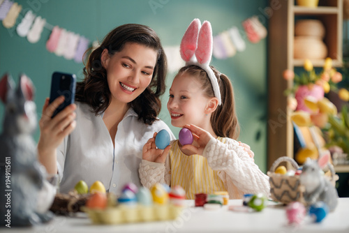 Happy Mother and Daughter Taking Easter Selfie While Decorating Colorful Eggs at Home