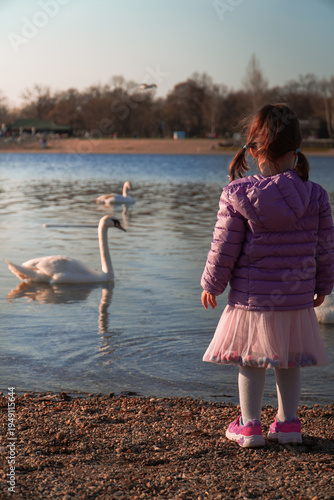 Obraz na plátně beautiful photo of a girl dressed in pink standing on the shore and watching a w