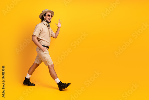 Konstfotografi Man in safari outfit walks confidently against a bright yellow backdrop adventur