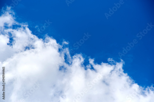 Diagonal composition of white clouds against a vibrant blue sky background