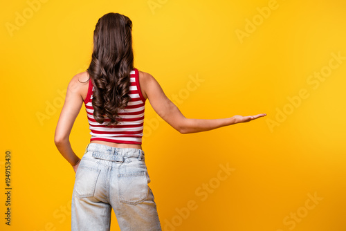 Konstfotografi Young woman with striped top and jeans poses against bright yellow background fo