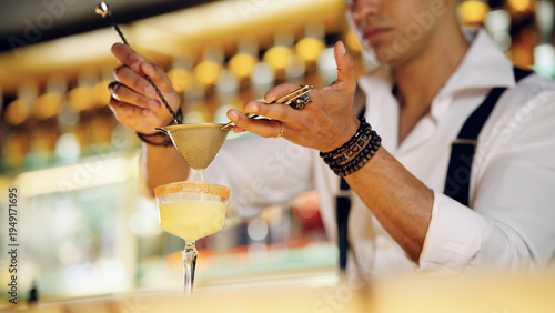 Schilderij op canvas Skilled bartender accurately straining a craft cocktail into a glass, creating a