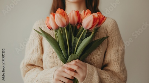 Woman Holds Bouquet of Tulips in Her Hands While Wearing a Sweater Indoors