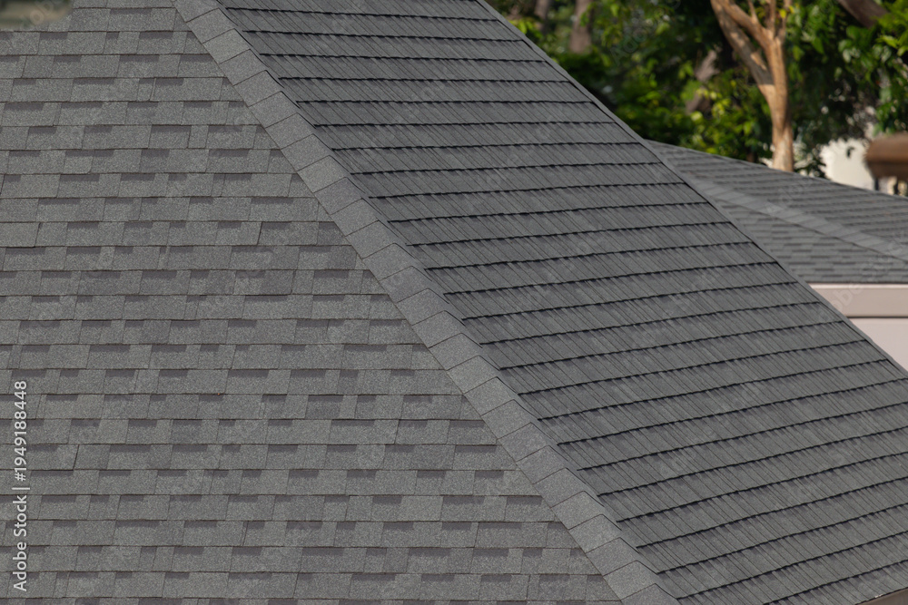 Naklejka premium Dark gray shingles line a sloped roof with neat rows