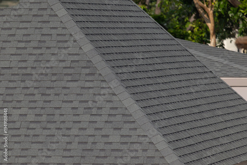 Dark gray shingles line a sloped roof with neat rows