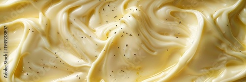 A creamy white sauce with black pepper sprinkled on top. The sauce is spread out in a long, thin line