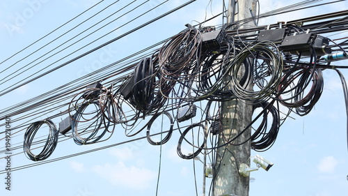 Tangle of cables and wires on the pole. Chaos of disorganized and tangled cables and wires on Thailand electrical poles in bottom view with selective focus.