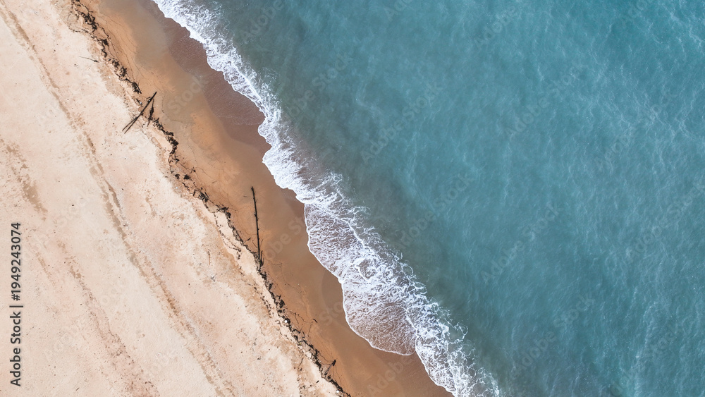 Obraz premium Tropical beach landscape from drone perspective showing turquoise sea and smooth sand coastline. Minimal natural background ideal for travel websites, resort promotions, and summer design projects.