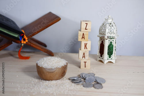 The background concept of Zakat: Rice on a wooden bowl, prayer beads, a remembrance, and scattered coins. Zakat is a form of obligatory charity in Islam. The concept of Islamic donation, or Zakat.
