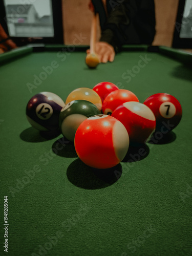 Billiard Balls on Green Pool Table with Player Preparing to Shoot