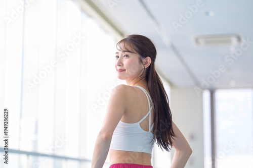 ジムで微笑むスポーツウェアの女性の後ろ姿