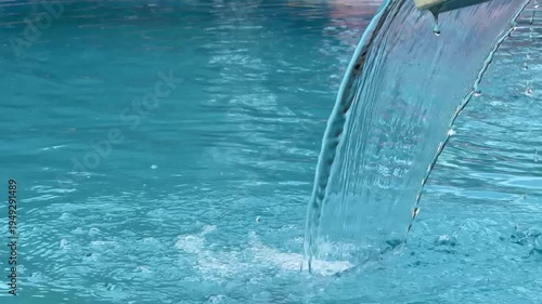 Clear water flowing into swimming pool creating relaxing ripples.