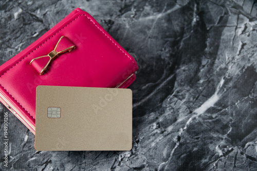 Bank card and red wallet on dark stone background close-up with copy space