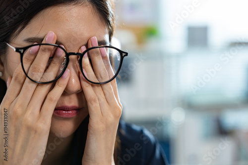 Foto Exhausted Asian woman feeling tired and experiencing deep stress at office rubs