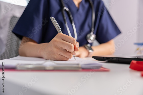 Konstfotografi Female doctor nurse in blue scrubs writing notes on clipboard using pen with ste