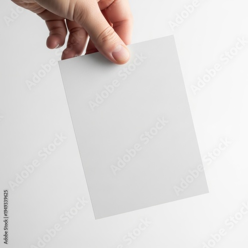A hand holding a blank white piece of paper