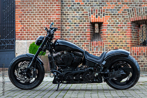 A custom black motorcycle parked against a brick wall