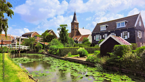 Traditional fishing village of Marken, Netherlands. Canal with bridge, traditional wooden houses and church