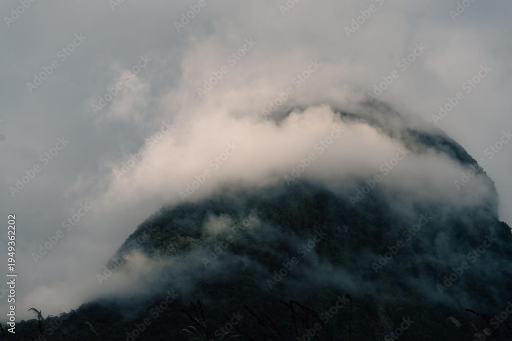 Fototapeta premium Sunrise through mountain range of Milford sound showing mountain peaks on a boat