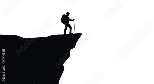 Hiker stands on a rocky cliff edge gazing into the distance silhouette