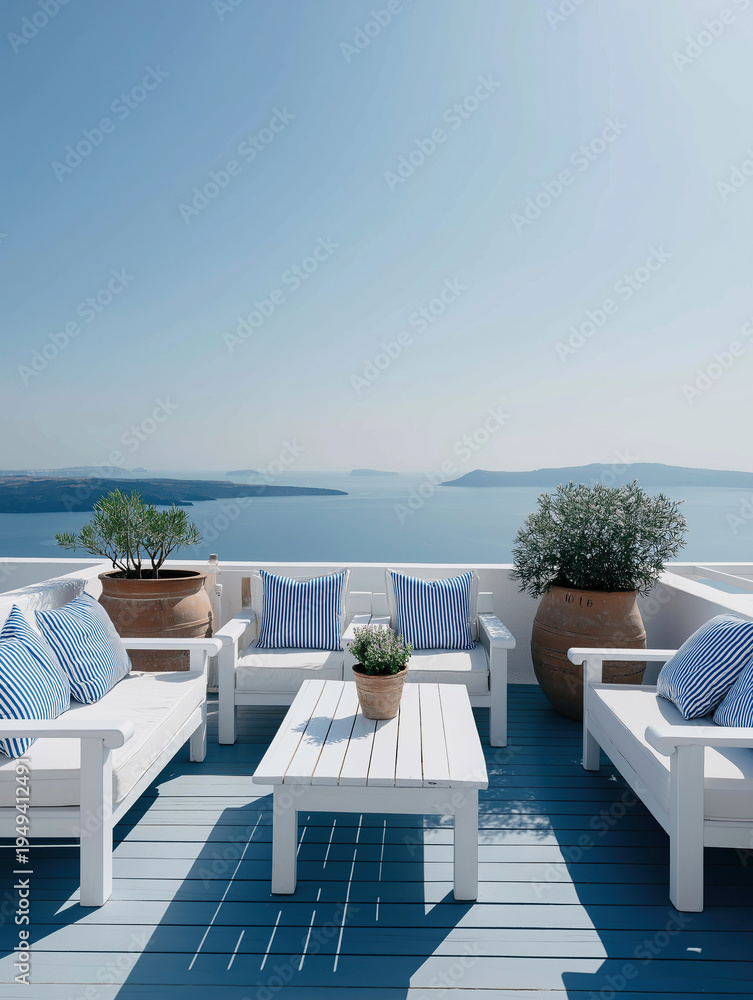 Fototapeta premium Bright white outdoor lounge overlooks the deep blue Mediterranean Sea under a clear sky in a typical Greek island setting.