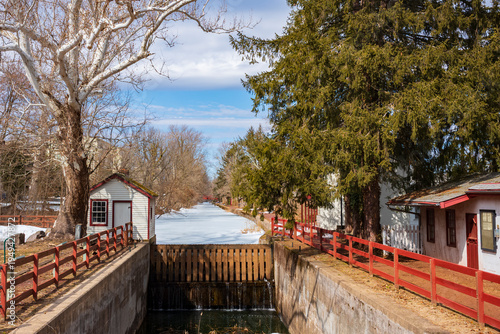 Foto A snow covered canal and a leafless birch tree glow in in the sunlight over a tow path and the Delaware Canal Trail during a cold winter day