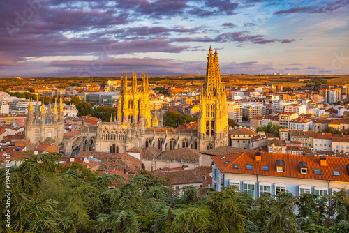 Panoramic view of Burgos Cathedral at sunset with the city skyline and old town rooftops. Gothic architecture of the UNESCO World Heritage site under a warm evening sky in Castile and Leon, Spain.