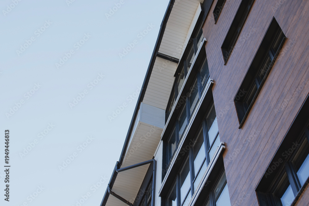 Obraz premium Commercial building exterior featuring horizontal dark wooden cladding panels and large black framed glass windows showcasing premium architectural design for business environments.