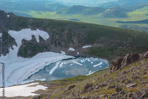Ice chunks floating in alpine lake in high mountain cirque. Floes in small la...