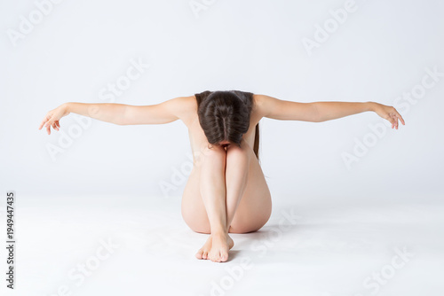 Natural beauty concept, young nude woman with long hair sitting on white background, skincare, body care and wellness