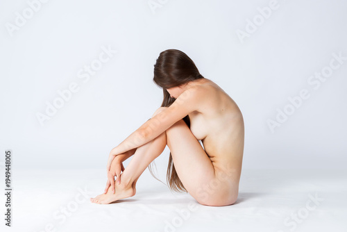 Natural beauty concept, young nude woman with long hair sitting on white background, skincare, body care and wellness