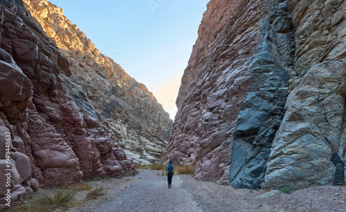 Dramatic landscape of a deep narrow canyon in lower Wadi Isla, Saint Katherine Protectorate in Egypt. High cliffs and steep granite walls. Red, green, black colors of magmatic rock. A female tourist.