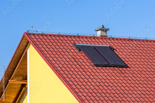 Fotografie A vacuum tube collector placed on the sloping red roof of a family house