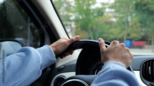 Close up of female hands spinning steering wheel driving a car practicing in city. Woman driver hands on steering wheel turning left practicing driving skill on parking. Slow motion.