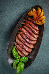 Top view sliced roasted duck breast with sauce and garnish