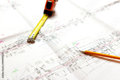 A sheet of construction drawings, a tape measure and a pencil