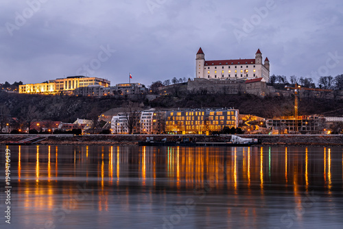 Canvas Print Bratislava Castle at dusk above the Danube with city lights in Slovakia