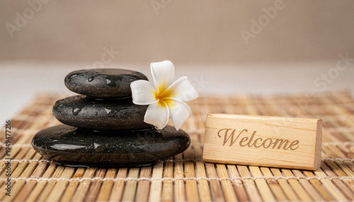 Zen Balance: Stack of Wet Dark Rocks with a Delicate White Flower and a Wooden 