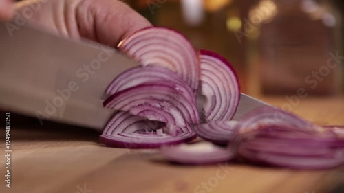 A chef cuts onions for a salad on a cutting board. Close-up.