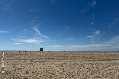 Wooden lifeguard tower on an empty Santa Monica beach under a clear blue sky, calm coastal atmosphere with classic California beach feeling.