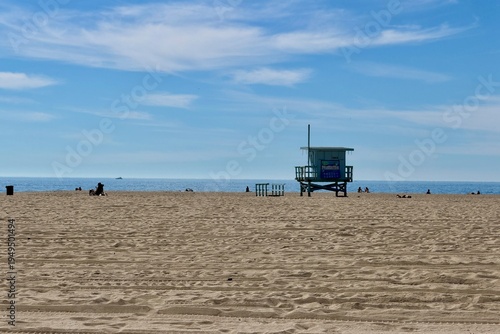 Wooden lifeguard tower on an empty Santa Monica beach under a clear blue sky, calm coastal atmosphere with classic California beach feeling.