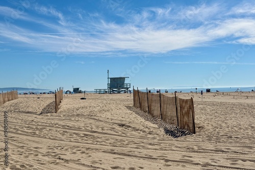 Wooden lifeguard tower on an empty Santa Monica beach under a clear blue sky, calm coastal atmosphere with classic California beach feeling.