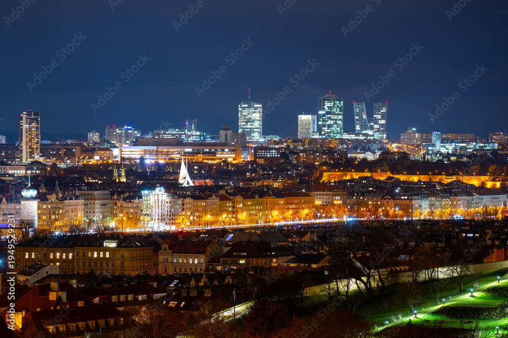 Obraz premium The Vltava Riverside with city lights shining in the evening. Pankrac stands tall in the background as the city comes alive at night.