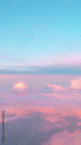 Aerial view from airplane window on ethereal beautiful sunset sky while early evening air flight through soft pink fluffy clouds with cotton candy texture. Vertical video 4K. Calming heaven background