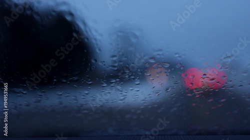 Cars moving in rain seen through wet windshield. Headlights traffic bokeh scene.