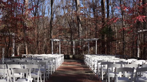 Outdoor woodland wedding ceremony aisle with white chairs
